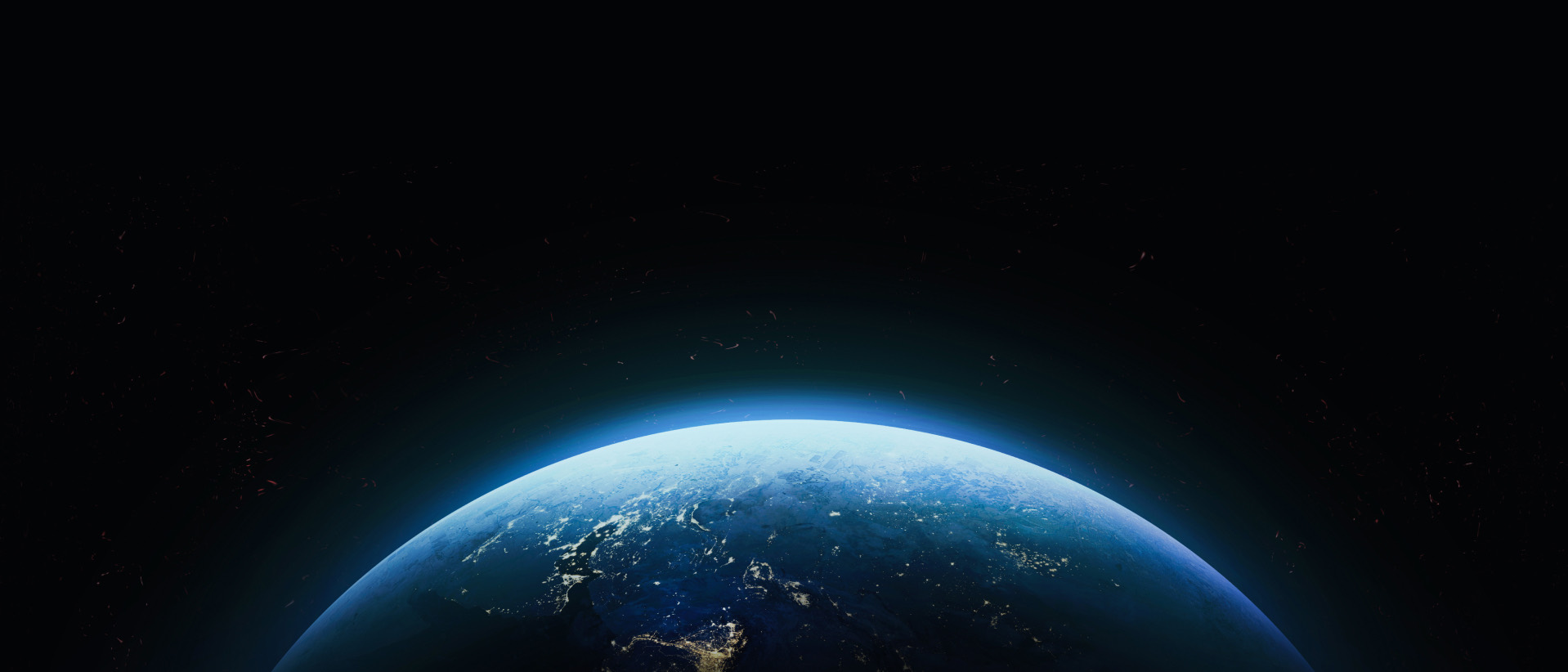 Earth at dawn seen from orbit: a curved horizon with city lights under a thin blue atmosphere.